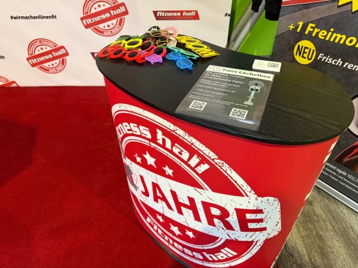 Promotionstisch mit bunten Dekos und Informationsmaterial zum Jubiläum.