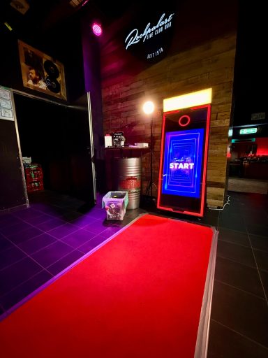 Roter Teppich vor einem Eingang mit Neonbeleuchtung und stilvoller Ausstattung.