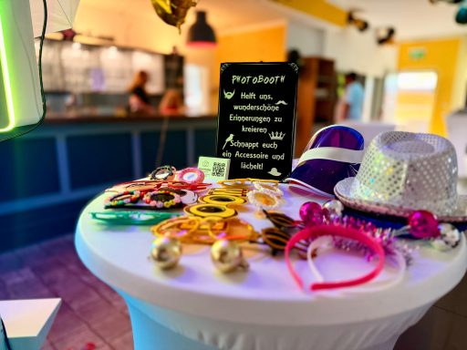 Bunte Partyaccessoires auf einem Tisch, darunter Hüte, Brillen und Schmuckstücke.